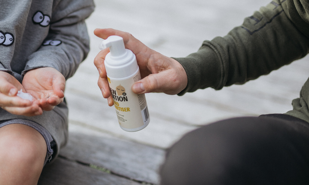 Dad helping son use the New Edition foaming Hand Sanitiser while sitting outsider on the deck