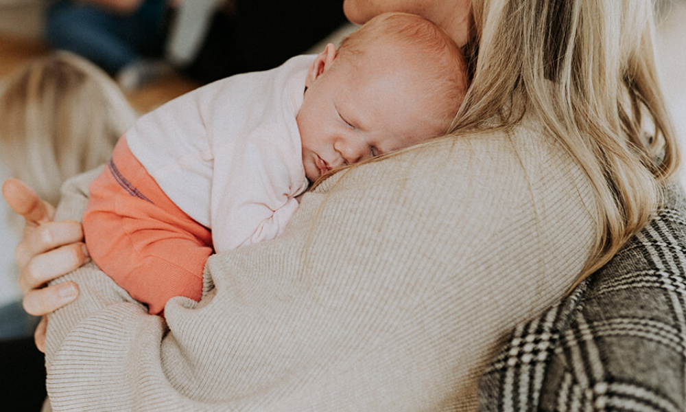 Newborn baby girl sleeping on mums shoulder