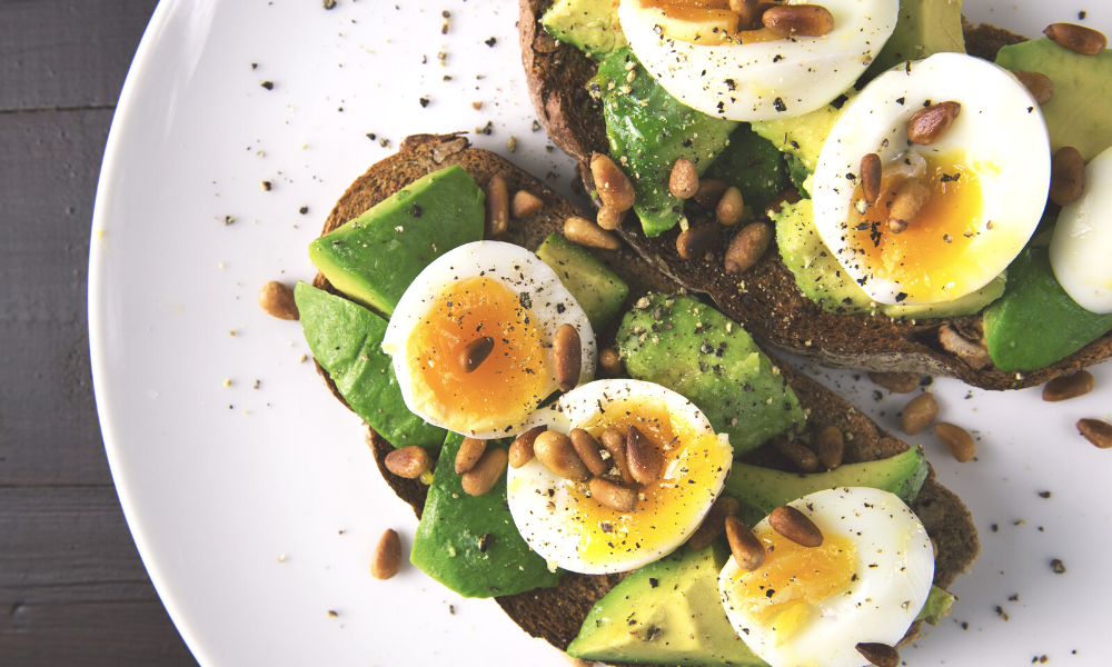 poached egg on smashed avocado toast with roasted pine nuts is a great meal for breastfeeding mums