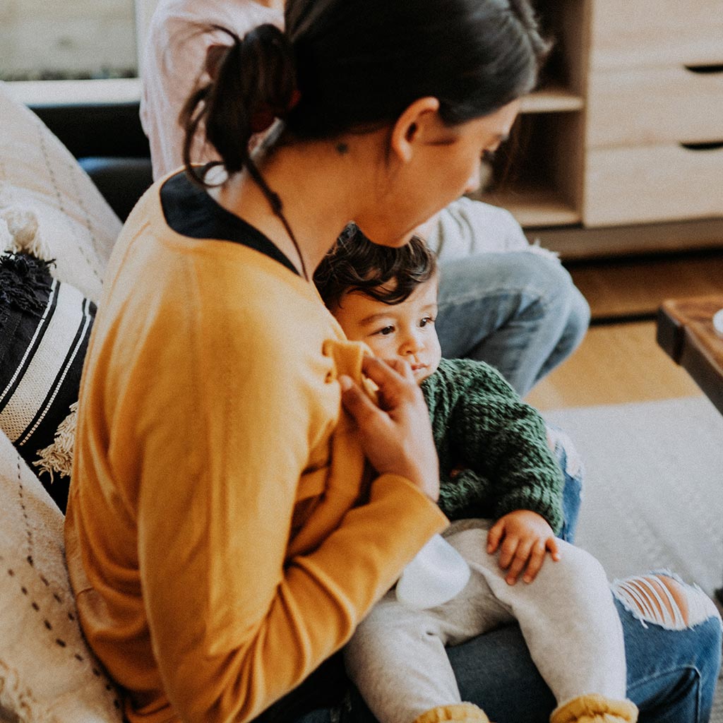 Mum holding baby while pumping with the Pumpd Breast Pump