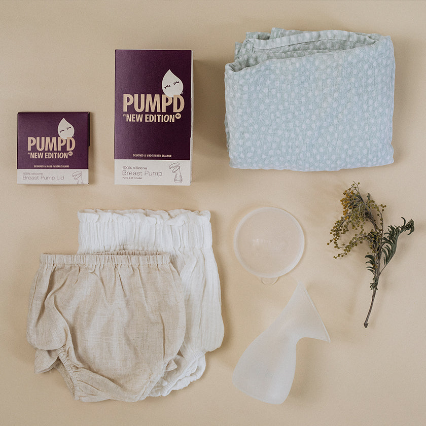 flatlay image of the Pumpd Breast Pump next to baby clothes and baby blanket