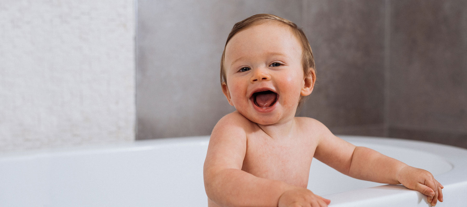 baby boy laughing and smiling in the bath