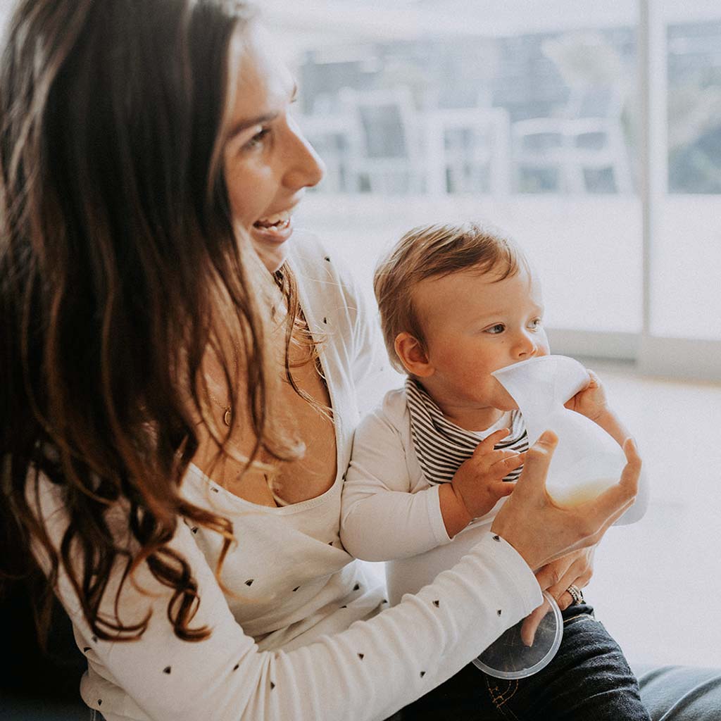 after pumping and collecting breast milk with the Pumpd breast pump mum is showing her baby and he is chewing the pump because he is teething