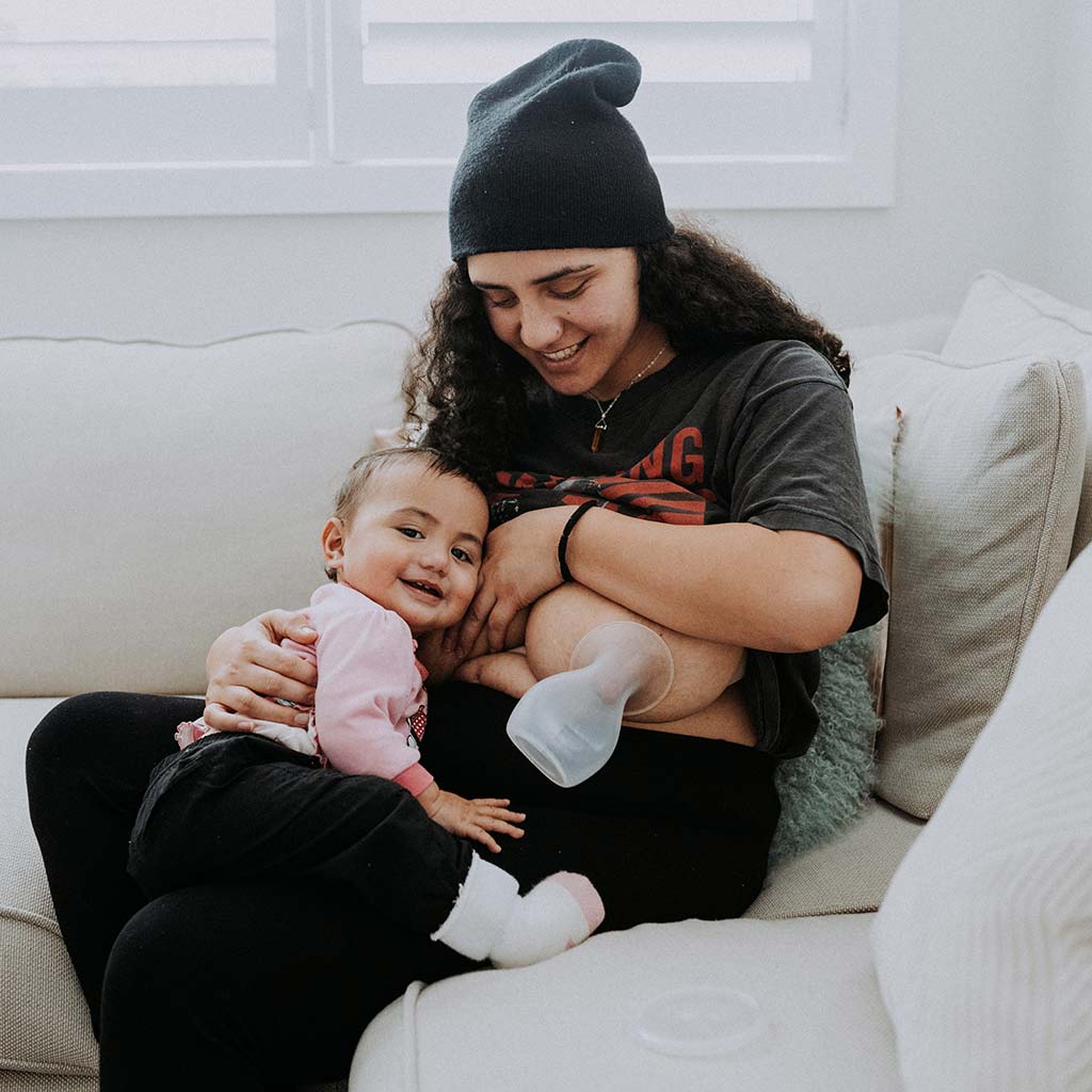 Maori Mum breastfeeding her daughter and using the Pumpd Pump which fits her large breasts comfortably