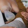 mum holding and breastfeeding son while using the Pumpd silicone breast pump to collect breast milk let down